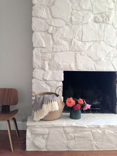 a white fireplace with flowers and a basket on the mantel in front of it