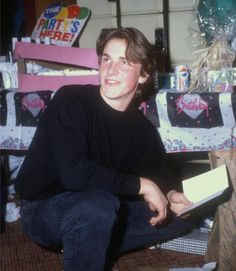 a young man sitting on the floor in front of presents