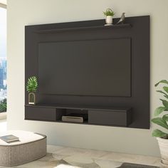 a flat screen tv mounted to the side of a wall next to a potted plant