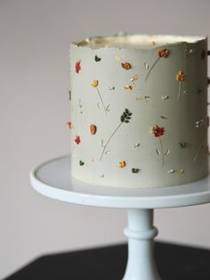 a white cake with flowers on it sitting on top of a table