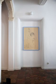 an empty room with a painting hanging on the wall and brick flooring in front of it