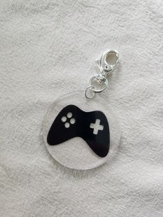 a black and white game controller keychain on top of a white cloth covered table