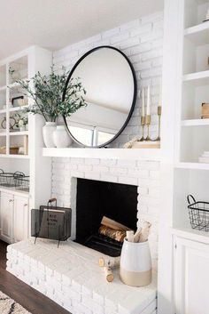 a white fireplace with a round mirror above it