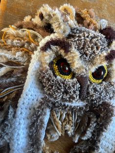 an owl made out of yarn sitting on top of a wooden table