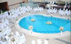 an aerial view of a pool with tables and chairs set up for a wedding reception