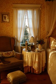 a bedroom with a bed, chair and table in it next to a large window