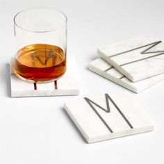 marble coasters with the letter m on them and a glass of whiskey in front