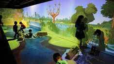 children are playing in an interactive museum with animals and trees on the wall behind them