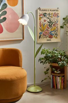 a living room with an orange chair, plant and poster on the wall above it