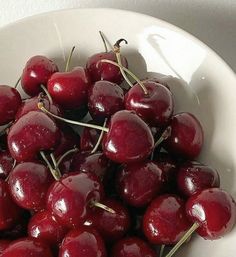 a white bowl filled with lots of cherries