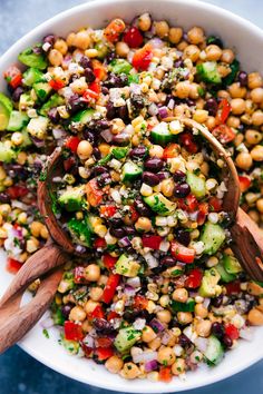 a white bowl filled with salad and wooden spoons