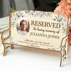 a wooden plaque with an image of a woman's face on it and flowers in the background