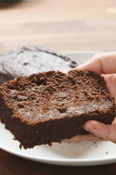 a person holding a piece of chocolate cake on a plate