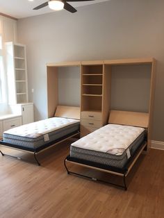 two mattresses sitting in the middle of a room with built - in bookcases