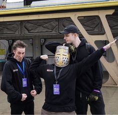 two men standing next to each other in front of a building with a mask on