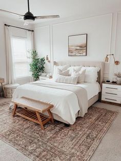 a bedroom with a bed, rug and two pictures hanging on the wall above it