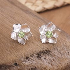 Many cultures associate peridot stones with prosperity and good fortune, as their green tone brings to mind Earth's abundance. Using these gems as the centerpiece, Balinese artisan Wayan Lasti crafts a pair of sterling silver stud earrings in a sweet flower shape. The accessory features a high polish finish for an elegant accent. Green Peridot Gemstones As Birthstones, Green Peridot Birthstone Gemstones, Green Gemstones For May Birthstone Gift, Lime Green Gemstone Jewelry In Sterling Silver, Peridot Gemstones Gift, Sterling Silver Lime Green Gemstone Jewelry, Lime Green Sterling Silver Gemstone Jewelry, Lime Green Peridot Jewelry For May Birthstone, Lime Green Birthstone Jewelry Gift