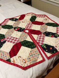 two quilted christmas coasters sitting on top of a white tablecloth covered bed