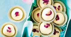 several cupcakes with pink flowers in them on a blue tablecloth next to a flower