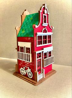 a paper model of a red house with a bicycle on the front and green roof