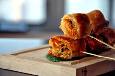 two pieces of food sitting on top of a cutting board with toothpicks sticking out of it