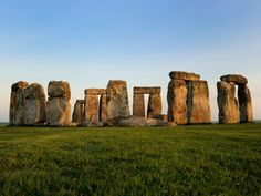 the stonehenge monument stands in an open field with green grass and blue sky