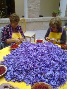 two women sitting at a table covered in purple flowers