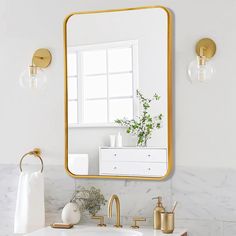 a bathroom with marble counter tops and gold accents on the mirror, along with brass faucets