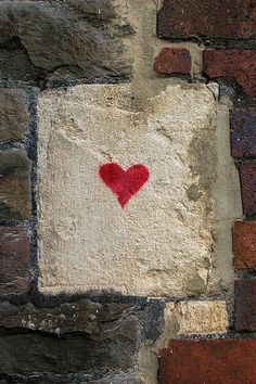 a brick wall with a red heart painted on it