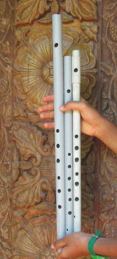 a woman holding four white flutes in front of a carved wall with intricate designs on it