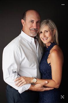 a man and woman are posing for a photo in front of a black background with their arms around each other