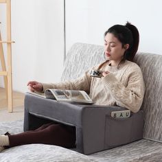 a woman sitting on a couch reading a book