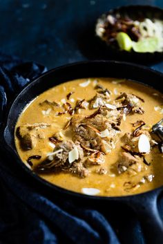 a close up of a bowl of food on a table with text overlay that reads badami gosh korma