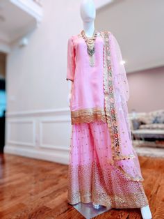 Gorgeous formal wear sharara outfit! 3 piece outfit, with pink three-quarter sleeve kameez with gold gotapatti on neckline and ghera on the front and back of the shirt. Simple lightweight net sharara with full gold work on the whole sharara. The set comes with a matching net dupatta with a gold and green floral border. Simple and elegant outfit. you can easily pair it with light or heavy jewelry, depending on the occasion. The embroidery and sequins are on super lightweight fabric, so you can fe Festive Pink Salwar Kameez With Gota Work, Pink Party Kurta With Zari Work, Pink Salwar Kameez With Sheer Dupatta For Party, Pink Party Salwar Kameez With Sheer Dupatta, Pink Party Kurta With Dabka Work, Pink Kurta For Wedding And Festivals, Bollywood Style Pink Kurta With Dabka Work, Festive Pink Sharara With Dabka Details, Pink Kurta For Wedding And Eid