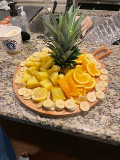 pineapple, oranges and bananas on a cutting board sitting on a kitchen counter