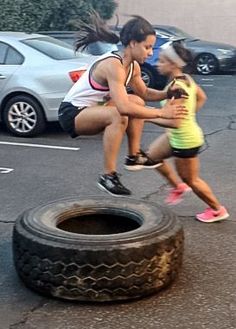 two people are playing with an old tire