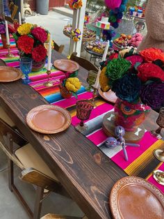 the table is set with colorful flowers and plates