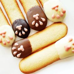 four cookies with pink and white icing on them are arranged in the shape of paw prints