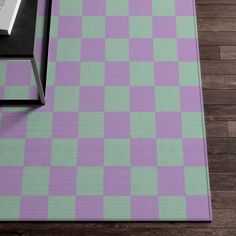 a purple and green checkered rug with a book on the floor next to it