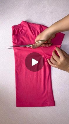 someone is cutting up a pink t - shirt with scissors