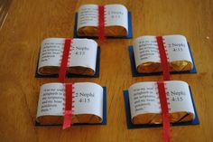 four pieces of paper wrapped in red ribbon sitting on top of a wooden table next to each other