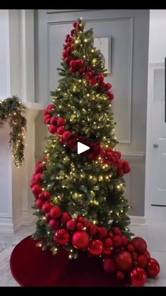 a christmas tree with red balls and lights in a living room decorated for the holidays