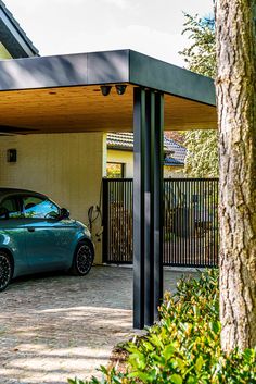 a blue car parked in front of a house next to a tree and shrubbery