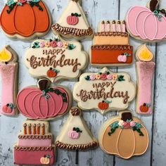 decorated cookies with candles and pumpkins are arranged on a white tablecloth, next to a wooden background