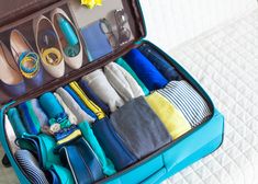 an open suitcase filled with lots of different types of clothing and accessories on a bed