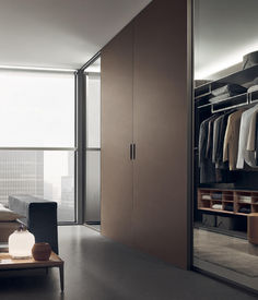 an open closet with clothes hanging on hangers in front of a bed and desk