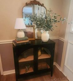 a small table with two vases and a mirror on it in front of a door