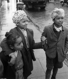 three children are walking down the sidewalk on a rainy day