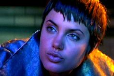 a close up of a person wearing a blue jacket and looking at the camera with an intense look on her face