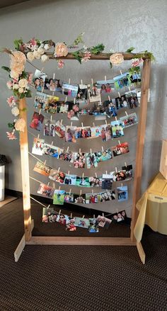 a wooden frame with pictures and flowers hanging from it's sides on a carpeted floor